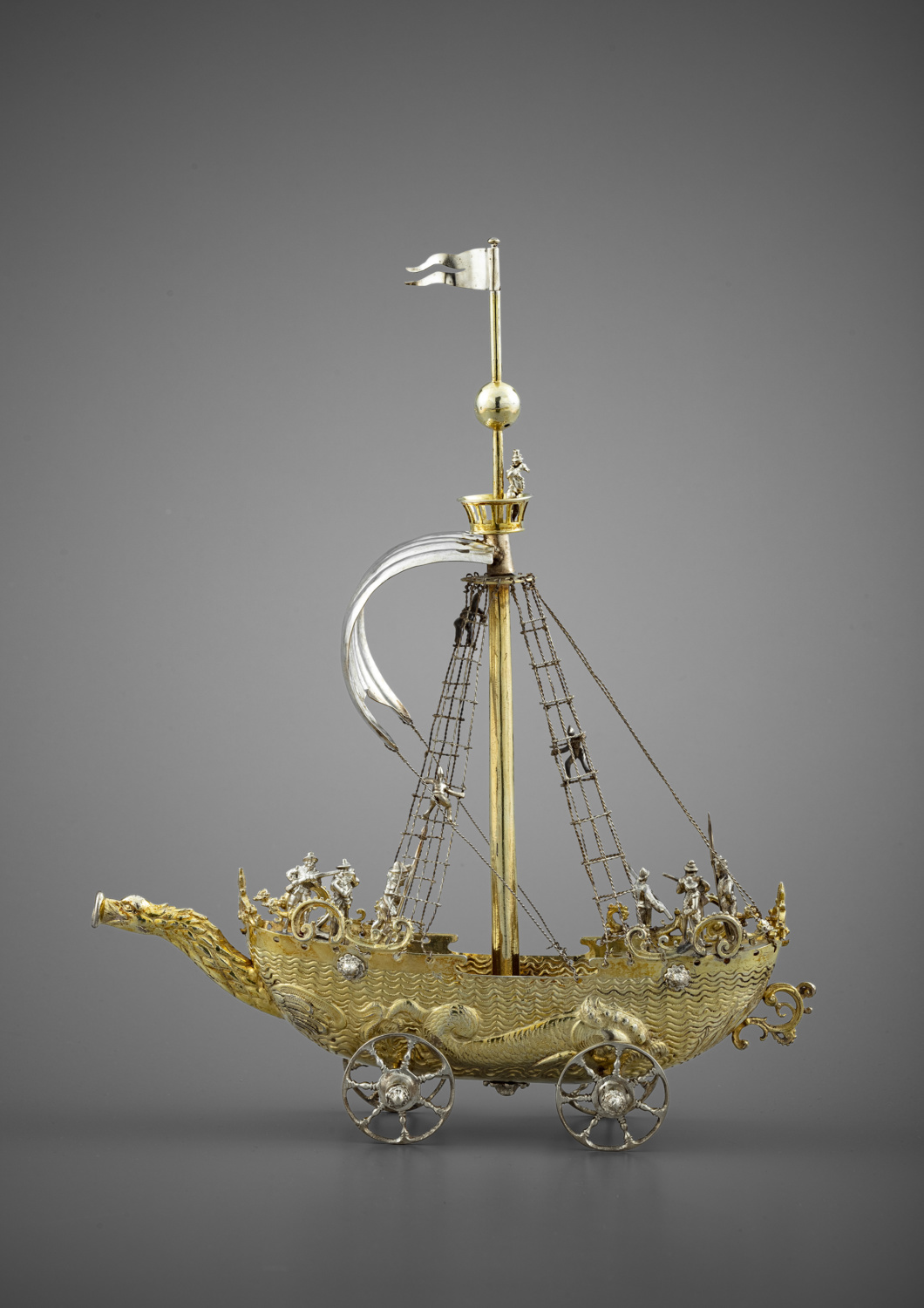 A silver and silver-gilt drinking cup in the shape of a vessel on wheels - Galerie Kugel